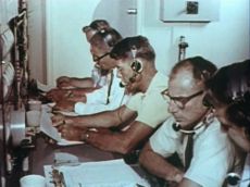 Astronaut Wally Schirra, CapCom for MA-5. in centre with systems engineers to his right and Bio-medical staff to his right:  Photo - ??